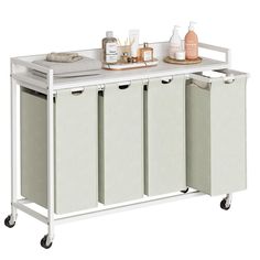 a white kitchen cart with three bins and two bottles on the top, next to some cleaning supplies