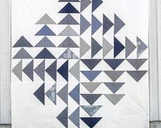 a quilt hanging on the side of a building with blue and gray triangles all over it