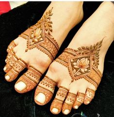 two feet with henna tattoos on them, one is showing it's intricate design