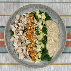 a salad with chicken, lettuce, carrots and dressing on a plate