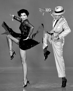 two people dressed in costumes and hats, one is dancing while the other holds his leg up