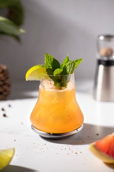 a glass filled with orange juice and garnish on top of a table next to slices of watermelon