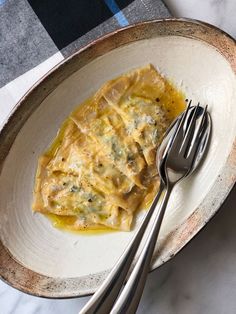 a white plate topped with ravioli next to a fork