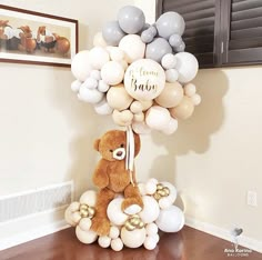 a teddy bear sitting on top of a bunch of balloons