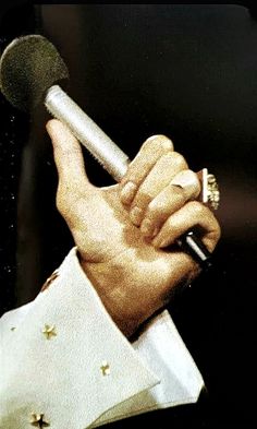 a close up of a person holding a microphone in one hand and wearing a ring on the other