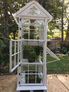 a small white greenhouse with plants growing inside