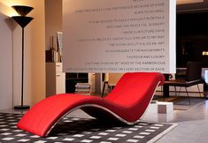 a red lounge chair sitting on top of a black and white checkered floor