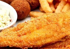 fried fish and french fries on a plate with coleslaw, breaded potato wedges