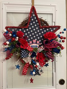 a patriotic wreath with red, white and blue flowers hanging from the front door for memorial day