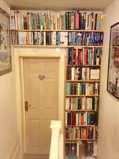 a bookshelf filled with lots of books next to a white door in a room