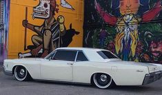 an old car parked in front of a colorful wall