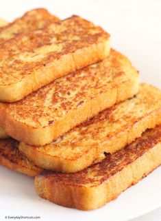 four pieces of french toast on a white plate, stacked up in the shape of squares