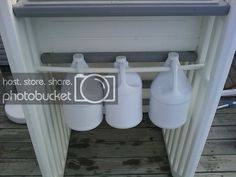 three white jugs sitting on top of a wooden floor