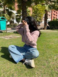 a woman sitting in the grass with her hands on her head