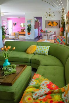 a living room filled with green couches and colorful pillows on top of each other