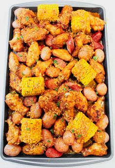 a pan filled with chicken and corn on the cob