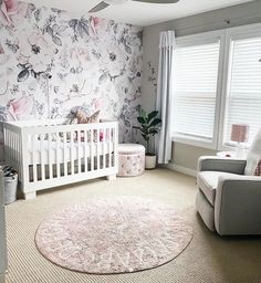 a baby's room with floral wallpaper and white furniture