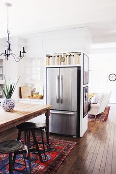 a kitchen with a table, refrigerator and chairs in it's center island area