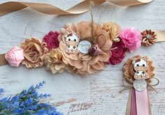 some flowers and ribbons on a white wooden table with pink, brown and blue flowers