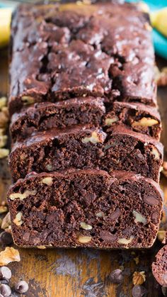 a loaf of chocolate banana nut bread on a wooden table next to bananas and nuts