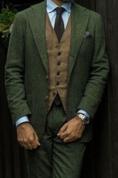 This is a forest green suit paired with a textured medium brown waist coast making for the perfect men’s style outfit. If you want this ensemble custom made for you, book an appointment at Giorgenti! Vintage Green Suit Men, Green Suit Brown Vest, Dark Forest Green Suit Men, Green And Brown Groom Suit, Enchanted Forest Men Outfit, Hobbit Wedding Suit, Green And Gold Prom Suit, Green Tweed Suit Wedding, Green Suit Aesthetic