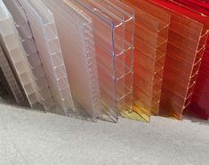 many different colored plastic sheets are stacked on top of each other in the same row