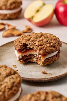 an apple and oatmeal cookie sandwich on a plate with apples in the background