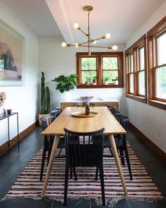 a dining room table with chairs and a potted plant in the corner next to it