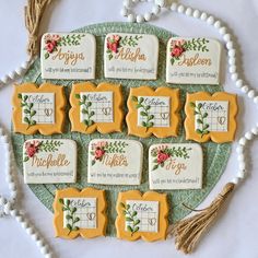 decorated cookies are arranged on a plate with tassels and beads around them, along with the names of each cookie