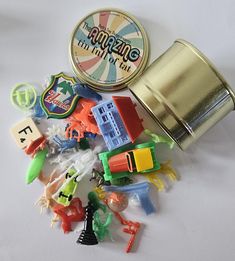 an assortment of toy items sitting on top of a white table next to a tin