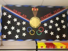 an olympic themed banner hanging on the wall in a room with other olympics decorations and bins