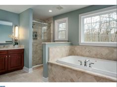 a bathroom with a tub, sink and large mirror in it's center area