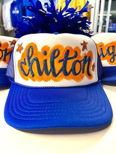 Everyone loves an original. That piece that no one else has. We've got you covered with our hand painted (and glittered) spirit truckers!  Cheer on your team or celebrate a bride-to-be or rock your favorite quote or hashtag ("slay")... these hats will surely have people asking, "where did you get that hat?" Our hats are constructed with rear mesh panels and a foam front. It features an integrated cotton sweatband, a pre-curved bill, and an adjustable plastic snap closure.  IMPORTANT NOTES:  No two hats will be the same. We do not use a template of any kind, so everything (placement, highlight, etc) is different.  We love to  customize hats for you with your choice of team/mascot and colors, even the color of the trucker, in some cases. Due to trademarking laws, some team names, sayings and Hand Painted Trucker Hats, Painted Trucker Hats, Paint Games, Team Mascots, Painted Letters, Custom Hand Painted, Team Names, Nashville Tn, School Spirit