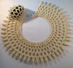 a white necklace with pearls is displayed on a table next to a black and white object