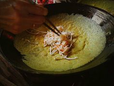 someone is cooking food in a skillet with chopsticks on the side,