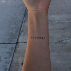 a woman's wrist with the word sanddae tattooed on her left arm, in cursive font