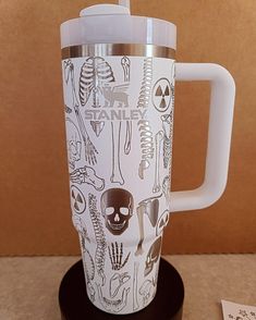 a white coffee cup with skeleton drawings on it and a straw sticking out of the lid