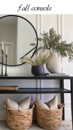 a black table with two baskets on it and a round mirror over the top that says fall console