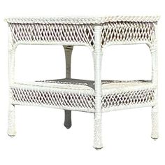 a white wicker side table with one shelf on it's legs and the other end