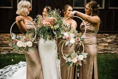 three bridesmaids pose with their bouquets in front of a barn