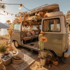 an old vw camper van is decorated with flowers and potted plants on the ground