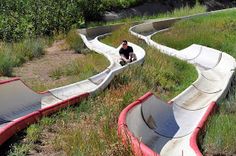 a man sitting on top of an upside down water slide in the middle of a field