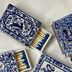 four matchboxes with matches in them on a white tablecloth, one is blue and the other has an animal design