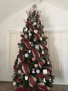 a christmas tree decorated with red, white and black plaid ribbon bows is in the corner of a room