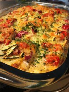 a casserole dish with tomatoes, cheese and herbs in it sitting on a stove