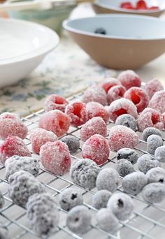 powdered sugar coated donuts on a cooling rack with blueberries and raspberries in the background