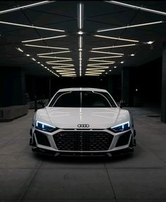 the front end of an audi car in a parking garage at night with lights on