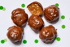 four chocolate covered donuts sitting on top of green polka dots