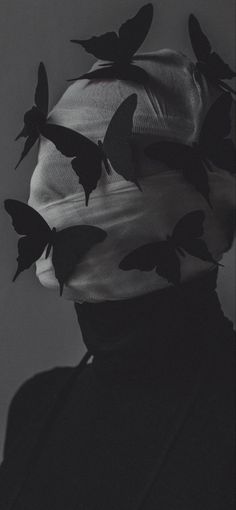 a woman with butterflies on her head in black and white