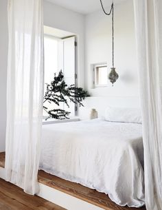 a bed with white sheets and curtains in a room